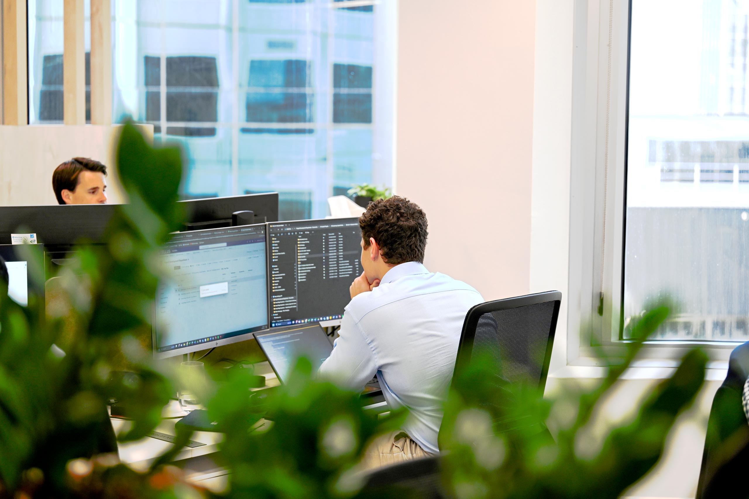 Images shows two employees working diligently at their desks. This image is representative of the breadth of employment opportunities at Tellus, in both operational FIFO roles and office roles.